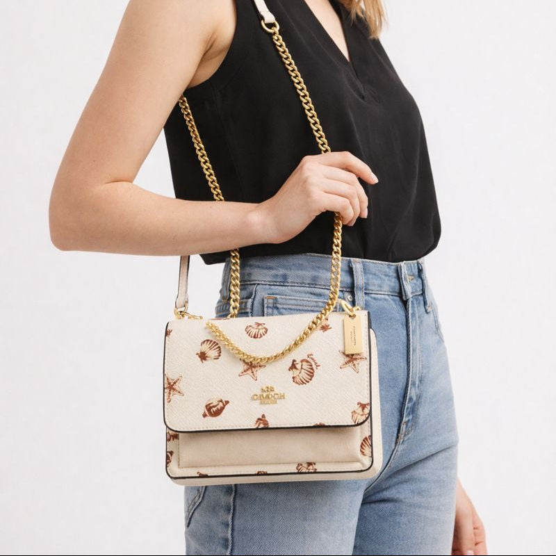 Cartera Coach beige con diseño de conchitas